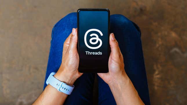 man holding a smartphone with the Threads app open