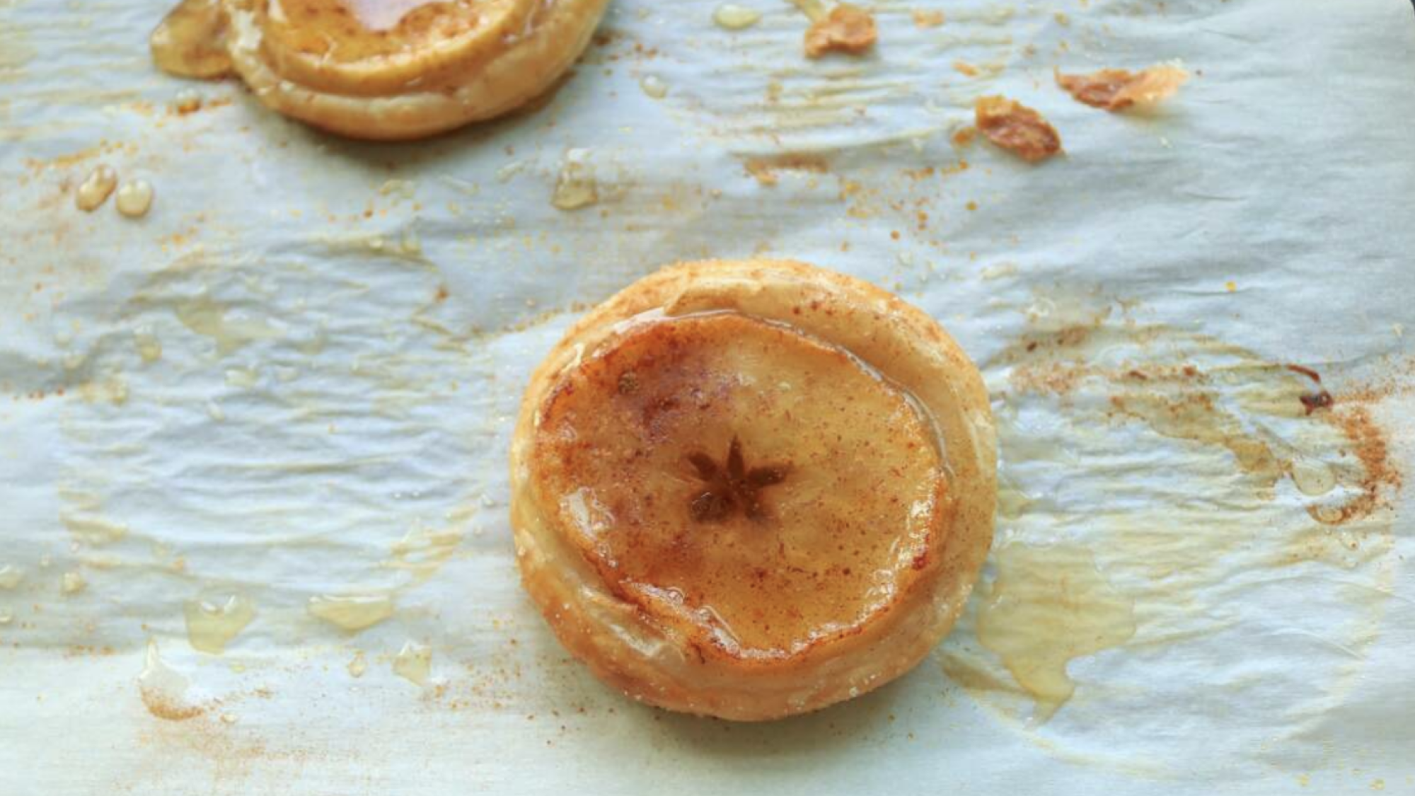 An apple puff on a parchment paper lined sheet tray.