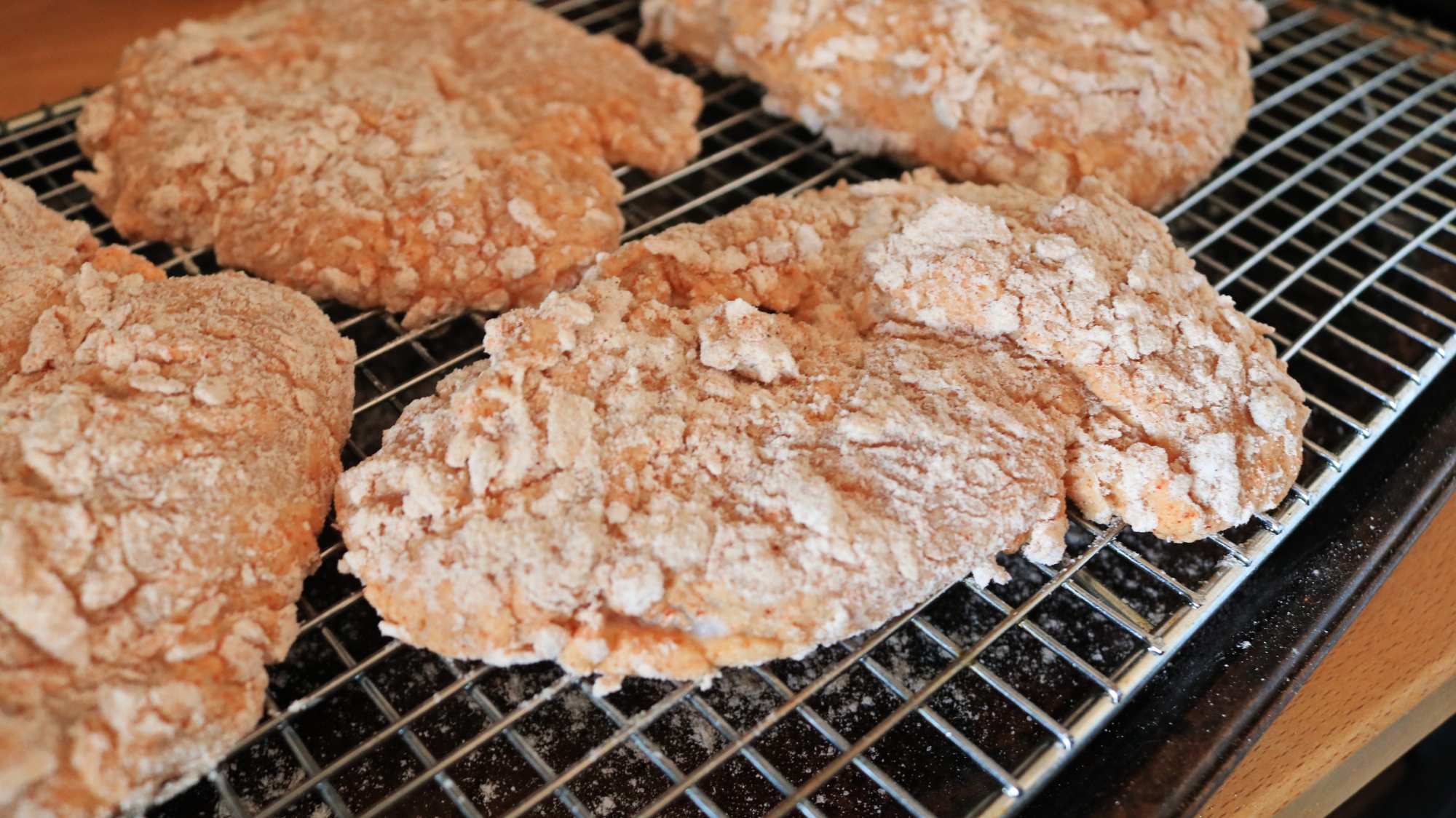 Raw chicken cutlets with breading on them.